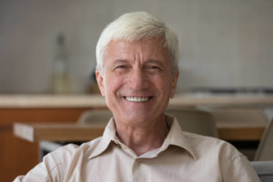 A smiling older man with dental implants