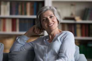 a smiling woman in a room with bookshelves in background