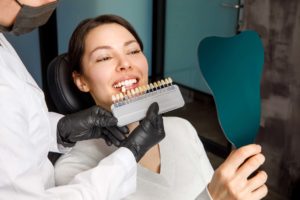 a dentist comparing model teeth to a woman's smile