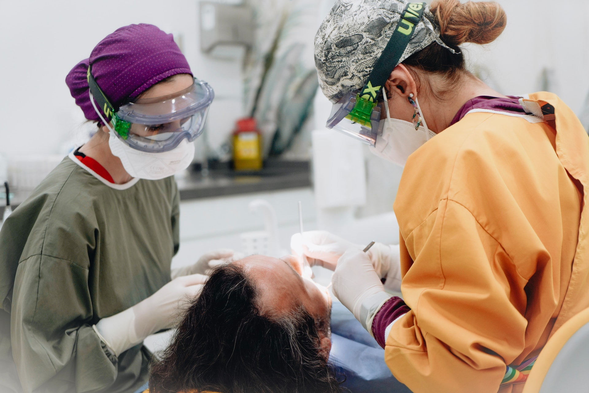 a dentist checking a patient's mouth with hygienist