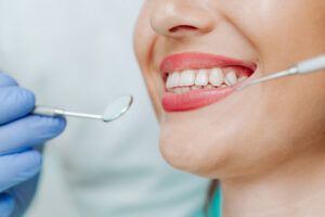 Picture of a woman smiling as a dentist cleans her teeth.