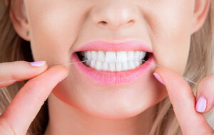 Image of young woman flossing her teeth 