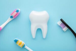 Picture of a white tooth figure and three toothbrushes against a blue background.