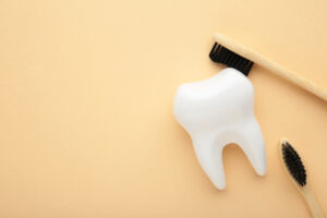 Picture of a white tooth figure and two toothbrushes against a yellow background.